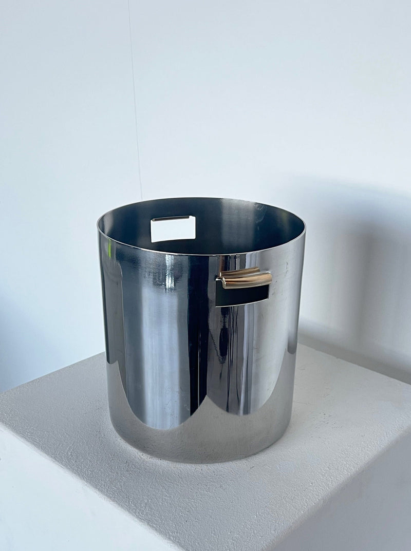 A Porter Studio Brutalist ice bucket with brass detail handle, placed on a white surface against a white wall.